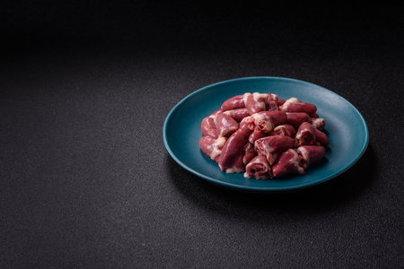 Raw chicken hearts with salt, spices and herbs on a dark concrete backgroundの写真素材