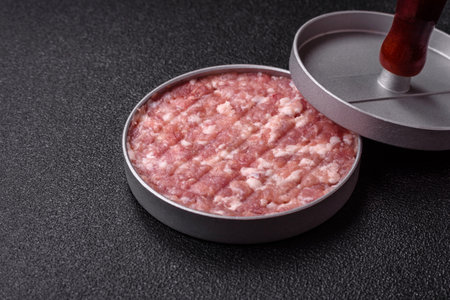Metal press for making minced meat cutlets for burgers on a dark concrete background