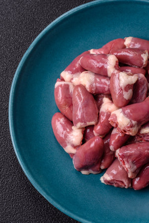Raw chicken hearts with salt, spices and herbs on a dark concrete backgroundの写真素材