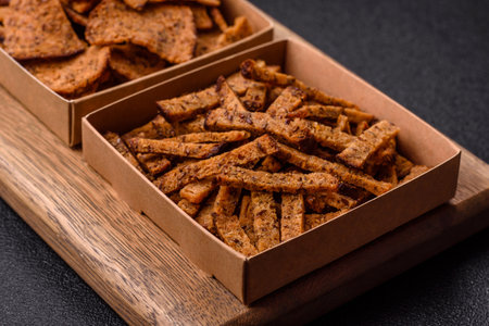 Crispy homemade brown bread crackers or croutons with seeds and grains, salt, spices and herbs on a...
