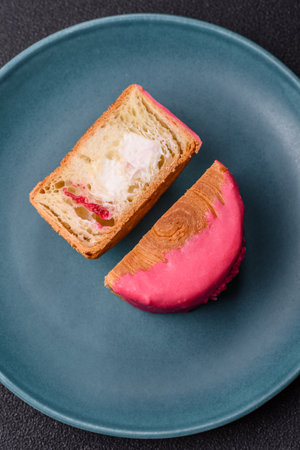 Round sweet roll croissant with raspberry cream filling on a dark concrete backgroundの写真素材