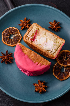 Round sweet roll croissant with raspberry cream filling on a dark concrete backgroundの写真素材