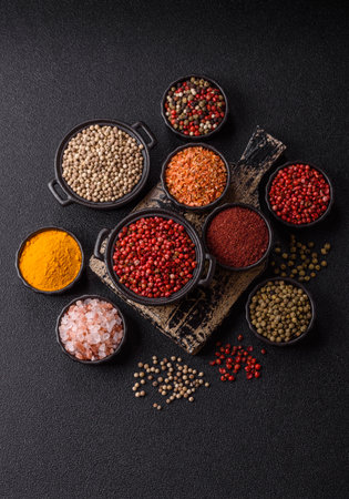 Variations of spices, allspice, turmeric, paprika, salt in ceramic bowls on a dark concrete...