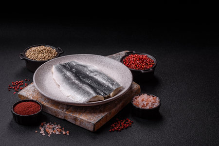 Herring fillet salted and marinated with salt, spices and oil on a dark concrete backgroundの写真素材