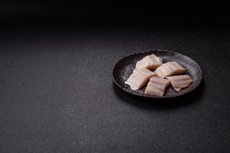 Herring fillet salted and marinated with salt, spices and oil on a dark concrete backgroundの写真素材