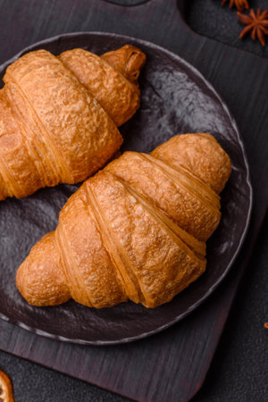 Sweet crispy croissants with chocolate filling on a dark concrete background