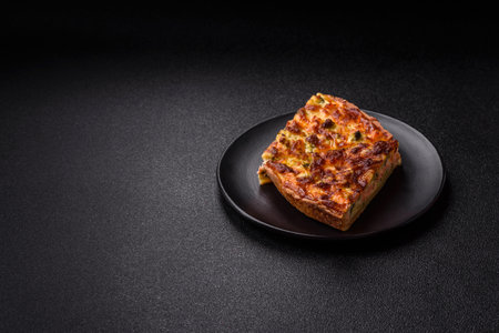 Delicious fresh quiche with broccoli, cheese, spices and herbs cut into pieces on a dark concrete...