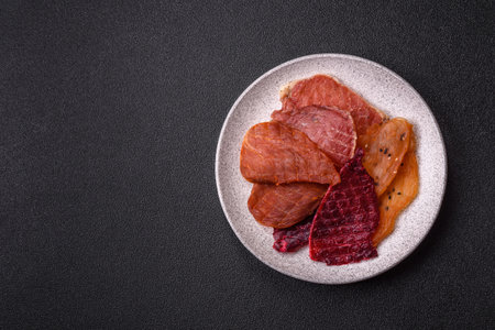 Jerky, dried pork meat with salt and spices on dark concrete backgroundの写真素材