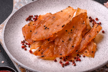 Jerky, dried chicken meat with salt and spices on a dark concrete background