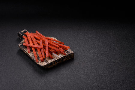 Jerky dried fish sticks with salt and spices on a dark concrete backgroundの写真素材