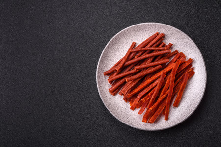 Jerky dried fish sticks with salt and spices on a dark concrete background