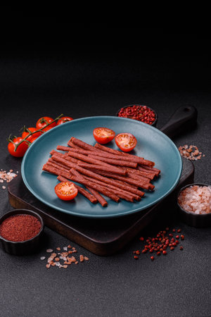 Jerky dried fish sticks with salt and spices on a dark concrete background