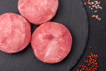 Two fresh slices of raw tuna fillet on a dark concrete background