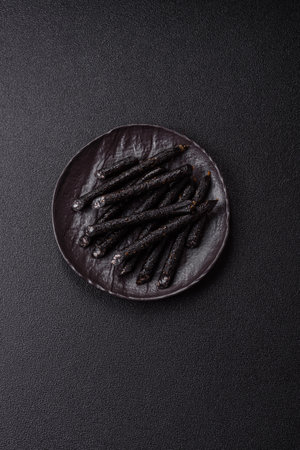 Sausage with salt, spices and herbs on a dark concrete background