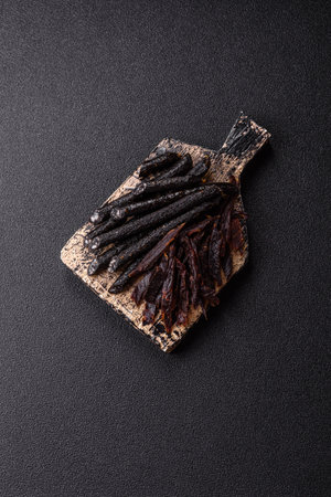 Sausage with salt, spices and herbs on a dark concrete background