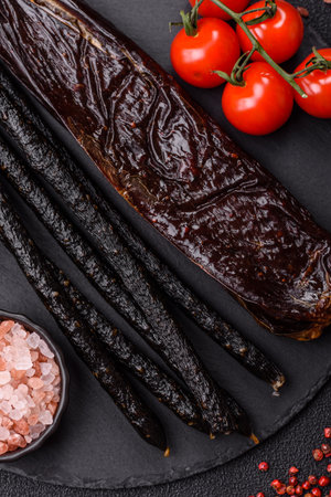 Sausage with salt, spices and herbs on a dark concrete background