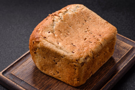 Brown bread with grains and seeds on a dark concrete background