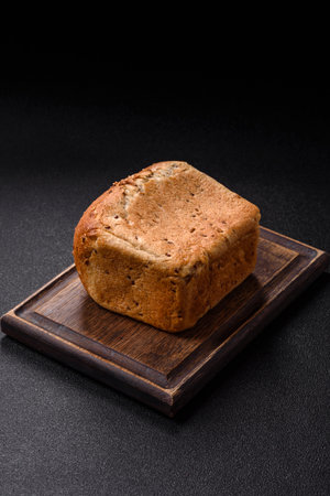 Brown bread with grains and seeds on a dark concrete background