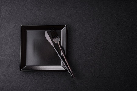 Empty ceramic round plate on dark textured background. Cutlery, preparation for dinnerの写真素材