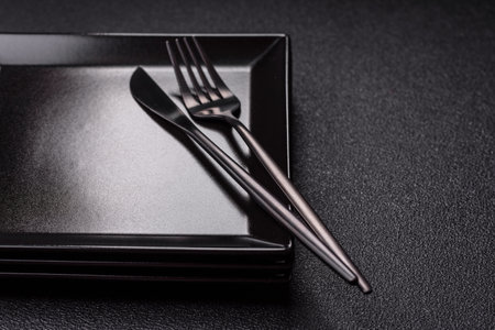 Empty ceramic round plate on dark textured background. Cutlery, preparation for dinner