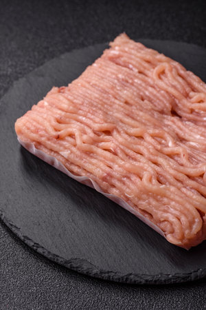 Raw minced meat with salt, spices and herbs on a dark concrete background