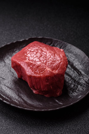 Raw beef tenderloin steak with salt and spices on a dark concrete backgroundの写真素材