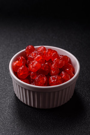 Dried sweet red pitted cherries or candied fruits on dark concrete backgroundの写真素材