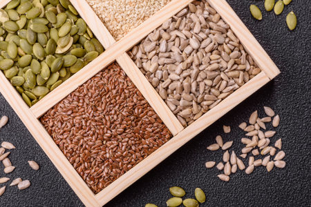 Sunflower, pumpkin, flax and sesame seeds in a wooden box as ingredients for making vegetarian and...