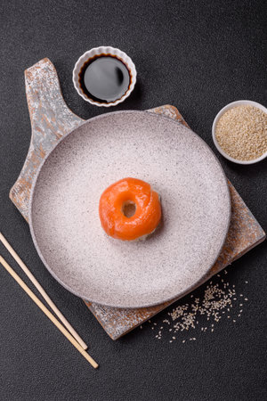 Donut shaped sushi rolls with salmon, shrimp and tuna, salt, spices and soy sauce on dark concrete backgroundの写真素材