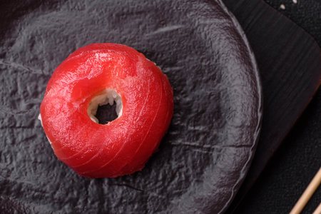 Donut shaped sushi rolls with salmon, shrimp and tuna on dark concrete backgroundの写真素材
