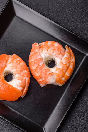 Donut shaped sushi rolls with salmon, shrimp and tuna, salt, spices and soy sauce on dark concrete backgroundの写真素材