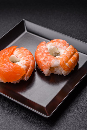 Donut shaped sushi rolls with salmon, shrimp and tuna, salt, spices and soy sauce on dark concrete backgroundの写真素材