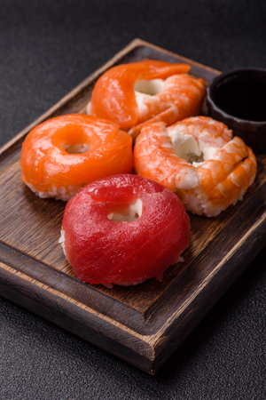 Donut shaped sushi rolls with salmon, shrimp and tuna on dark concrete backgroundの写真素材