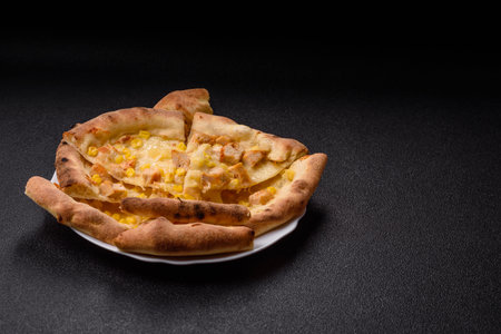 Hawaiian pizza with chicken, pineapple, and cheese on dark concrete backgroundの写真素材