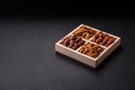Wooden box with four sections filled with nuts almonds, shelled almonds, cashews, hazelnutsの写真素材