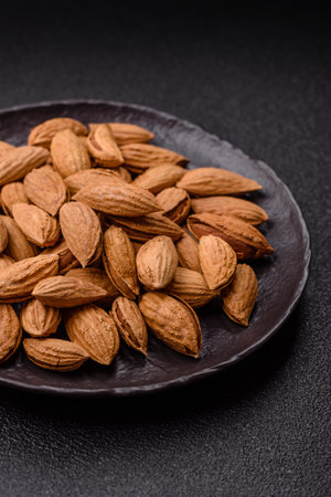 Roasted or raw almond nuts in bowl on dark concrete background