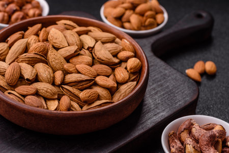 Roasted or raw almond nuts in shell in bowl on dark concrete backgroundの写真素材