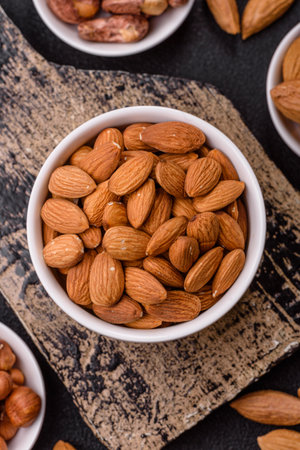 Roasted or raw peeled almonds in bowl on dark concrete backgroundの写真素材