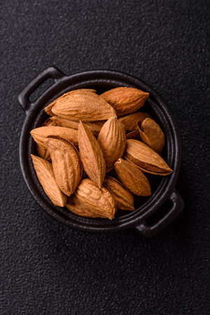 Roasted or raw almond nuts in shell in bowl on dark concrete backgroundの写真素材