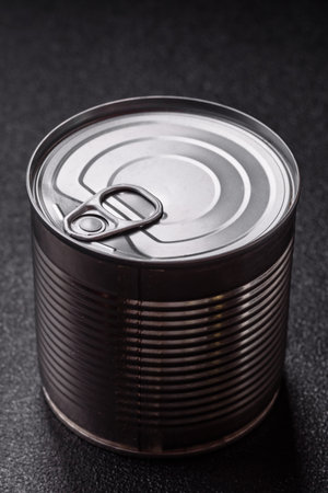 Metal cylindrical can with canned food on dark concrete background