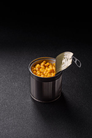 Sweet yellow canned corn in bowl on dark background