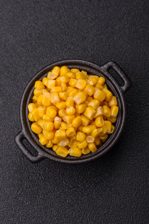 Sweet yellow canned corn in bowl on dark concrete background