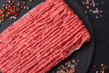 Raw ground beef or pork with salt and spices on dark concrete backgroundの写真素材