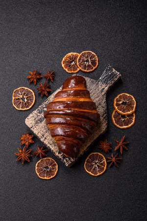 Sweet fresh crispy croissant with chocolate filling on dark concrete backgroundの写真素材