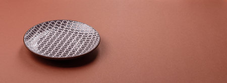 Empty ceramic plate on a monochrome brown background. Empty plate with cutlery on a dining tableの写真素材