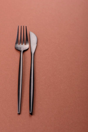 Knife and fork, cutlery on a brown dining table. Utensils and crockery for preparing dinnerの写真素材