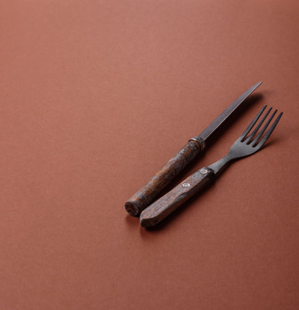 Knife and fork, cutlery on a brown dining table. Utensils and crockery for preparing dinnerの写真素材