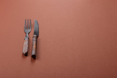 Knife and fork, cutlery on a brown background. Utensils for preparing dinner
