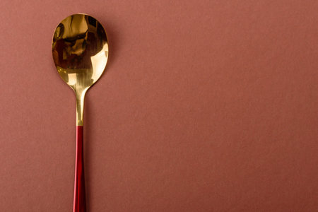 Empty metal spoon on a brown background.