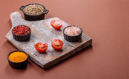 Wooden cutting board with bowls of ingredients on a brown background.の写真素材